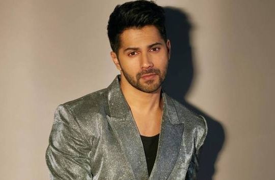 Varun Dhawan smiling at a film premiere, showcasing his charisma and star power in Bollywood