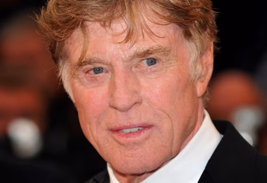 Robert Redford smiling at a film premiere, celebrating his Hollywood career and legacy