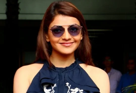 Kajal Aggarwal smiling and waving during her first public appearance after death hoax, looking radiant and happy in a stylish outfit